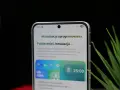 Telefon z interfejsem One UI 8.5 pokazuje ekran pobierania aktualizacji oprogramowania. Widoczny jest zegar 25:00.