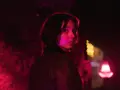Młoda kobieta z zaciekawieniem spogląda przez ramię w mrocznym, neonowym otoczeniu. Czy to scena z nowego serialu Netflix?