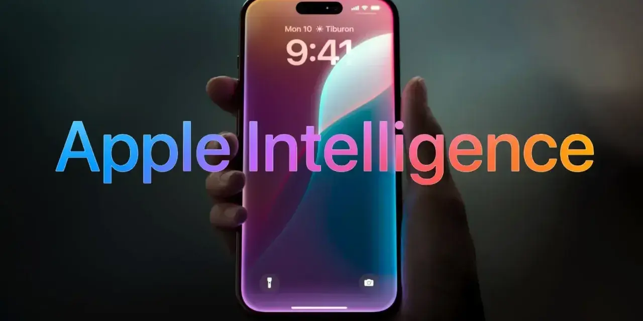Dłoń trzyma smartfon z ekranem blokady, na którym widnieje napis "Apple Intelligence" w tęczowych barwach.