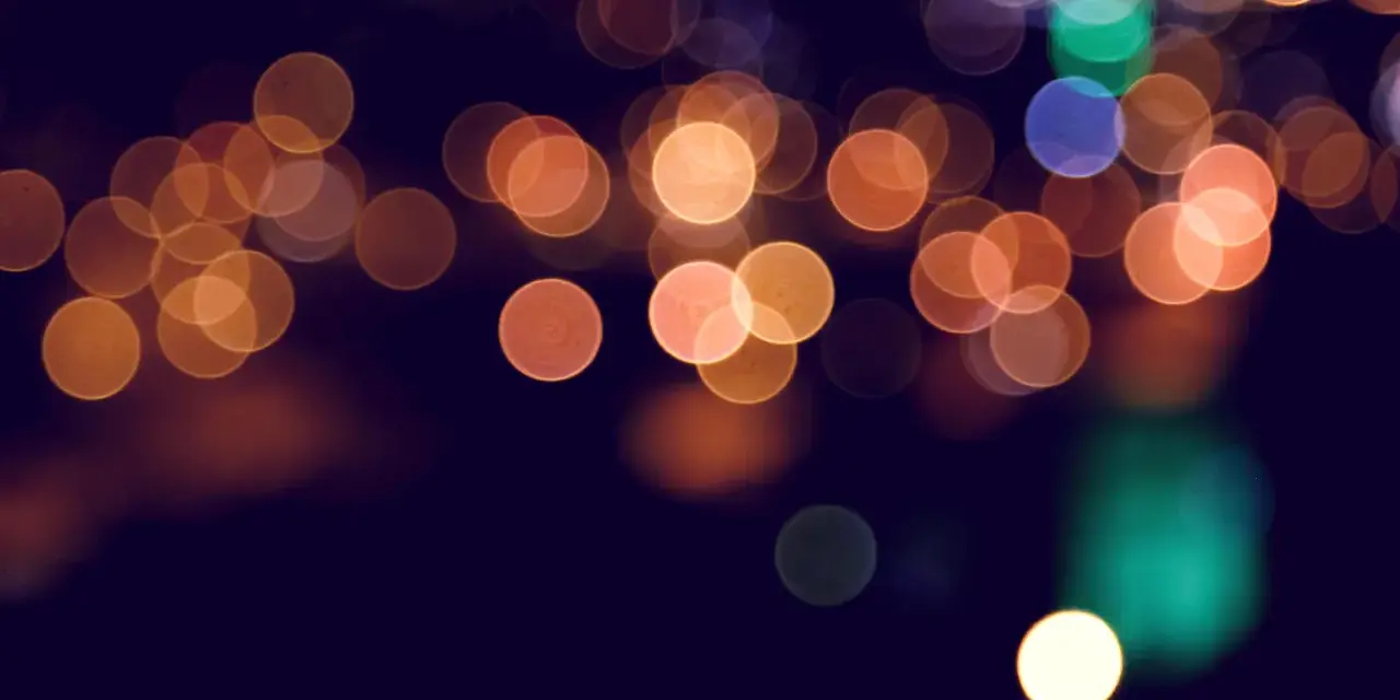 Rozmyte, okrągłe światła tworzą magiczny **bokeh** na ciemnym tle.