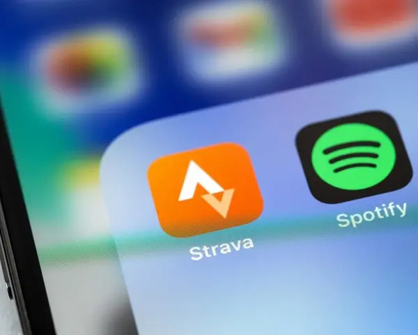 Ikona aplikacji Strava, idealna do śledzenia tras rowerowych, obok Spotify na ekranie smartfona.