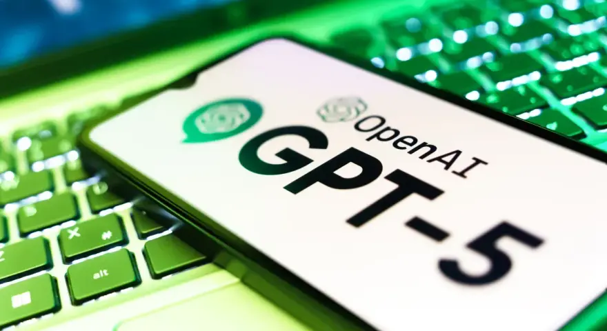 Ekran smartfona z logo OpenAI i napisem GPT-5 leży na podświetlanej zielonej klawiaturze.