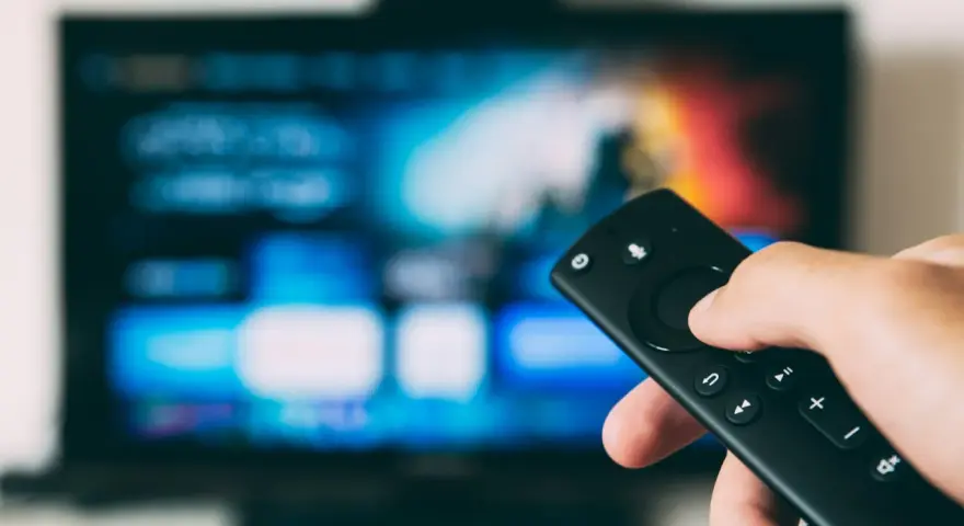 Ręka trzymająca pilot do telewizora, gotowa do nauki, jak zainstalować aplikacje na telewizorze.
