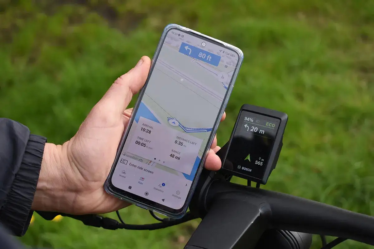 Smartfon z mapą i nawigacją rowerową obok wyświetlacza Bosch. Idealna aplikacja na rower do planowania trasy i śledzenia postępów.